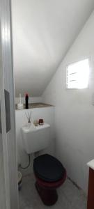 a white bathroom with a toilet with a black seat at Casa in San Clemente del Tuyú