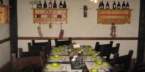 a dining room with a long table with bottles of wine at Pension Podul Turcului in Moieciu de Jos