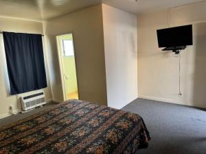 a bedroom with a bed and a flat screen tv at El Rancho Motel, Pasadena in Pasadena