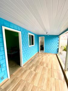 Habitación vacía con una pared de ladrillo azul y suelo de madera. en Casa inteira em Pontal do Sul, en Pontal do Paraná