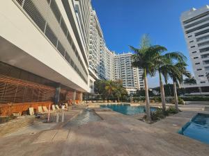a hotel swimming pool with palm trees and buildings at Apartamento con salida al Mar in Santa Marta