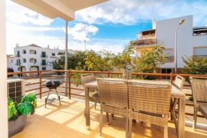 a balcony with chairs and a table and a grill at Cabanas Beach Apartment in Cabanas de Tavira