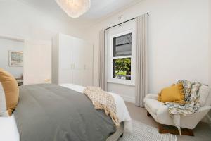 a bedroom with a bed and a chair and a window at Adelaide Hills Luxury Cottage - The Gladys in Carey Gully