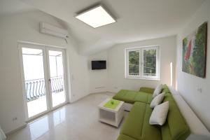 sala de estar con sofá verde y ventanas en Apartments Petrovac, en Zavala