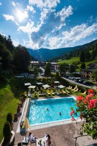a pool with chairs and umbrellas in a resort at Hotel Der Waldhof in Zell am See