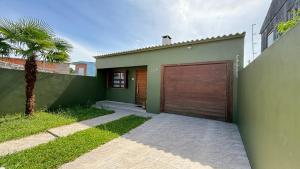 a green house with a garage with a palm tree at Casa do Sobrado in Bagé