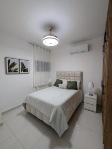 a white bedroom with a large bed and a lamp at Marbella in San Felipe de Puerto Plata