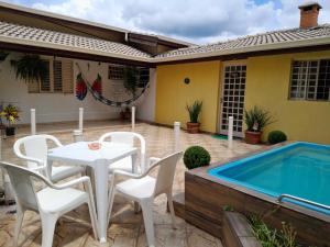 a patio with a table and chairs and a swimming pool at Cantinho do Paraíso in Águas de Lindóia