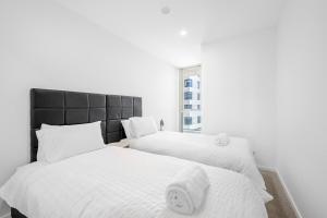 two beds with white sheets and a black headboard at Modern 2 Bedroom Apartment in Phillip with Parking in Phillip
