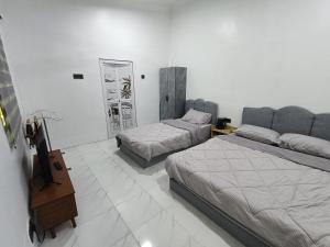 龙运Teratak Adamia Roomstay 04的有两张床和一面镜子的酒店房间