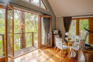 a dining room with a table and chairs and large windows at Bickley Tree Stay in Bickley