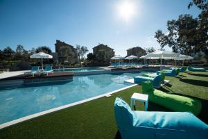 a swimming pool with lounge chairs and umbrellas at Lavender Cove in Korfos
