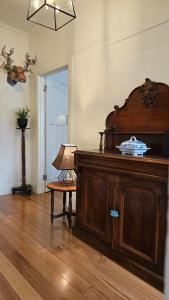 a room with a wooden cabinet and a table with a lamp at 'The Gardenia' Trentham in Trentham