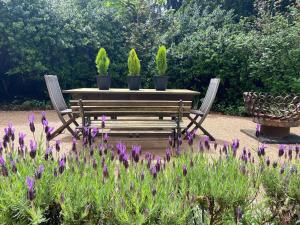 a table and chairs with plants and purple flowers at 'The Gardenia' Trentham in Trentham