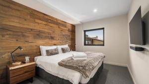 a bedroom with a wooden accent wall at Burramungee - 5 Bedroom Chalet in Mount Hotham