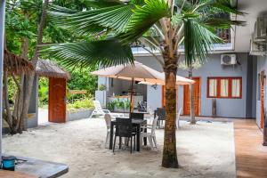 a table with chairs and an umbrella on the beach at Sea View Villa Ukulhas in Ukulhas