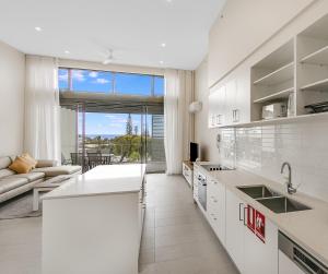 カバリタ・ビーチにあるCabarita Beachside Apartments 31の白いキャビネット付きのキッチン、リビングルーム +1枚の写真