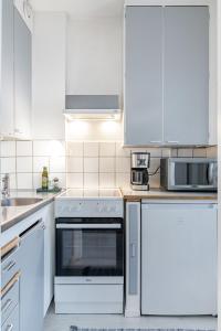 a kitchen with white cabinets and a stove top oven at Compact Studio with Balcony next to Railway Station in Lahti