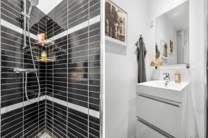 a bathroom with black tiled walls and a sink at Ryethave lejlighed ved Ryetvej i Værløse in Værløse