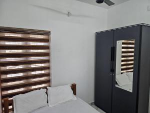 a bedroom with a bed and a cabinet and a mirror at MetroNova Homes - Furnished stay in Ambalappuzha in Alleppey