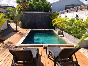 a swimming pool with two chairs on a wooden deck at Studio in Saint-Pierre