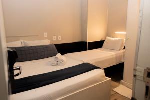two beds in a hotel room with shoes on them at Hotel Aero Sleep Campinas in Campinas
