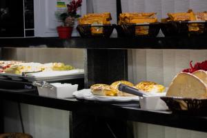 a shelf with several plates of bread and pastries at Hotel Aero Sleep Campinas in Campinas