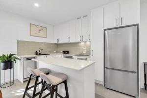 a white kitchen with a large white counter and stools at Your Noosa HQ - modern apartment near everything! in Noosaville