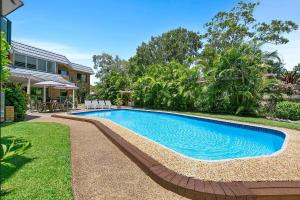 a swimming pool in a yard next to a house at Your Noosa HQ - modern apartment near everything! in Noosaville