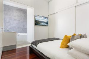 a white bedroom with a bed and a bathroom at Harbourfront 3 Bed 2 Bath Opposite Manly Wharf With Harbour Views in Sydney +17 photos
