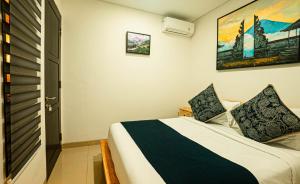 a bedroom with a bed and a painting on the wall at Villa Mandee Guest House in Uluwatu +15 photos
