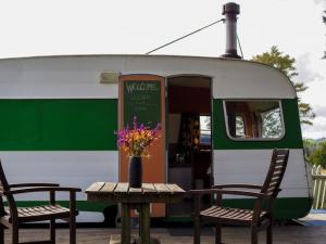 a table with a vase of flowers on it next to a train at Down to earth NZ in Kerikeri