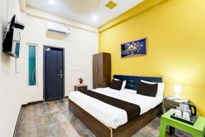 a bedroom with a large bed and a yellow wall at OYO Hotel O Arjun Ganj in Lucknow