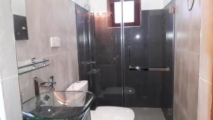 a bathroom with a toilet and a glass shower at New Rani Inn in Negombo