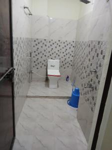 a bathroom with a toilet and a blue trash can at Budget Stay for Family with Atulyam in Prayagraj