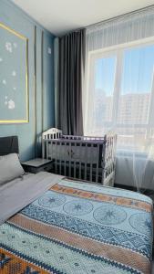 een slaapkamer met 2 bedden, een wieg en een raam bij Central Lifestyle in Astana