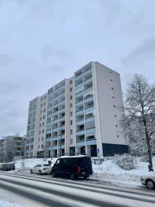 a large white building with cars parked in front of it at Cozy Studio next to Metro & Mall in Espoo