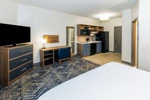 a hotel room with a bed and a desk with a television at Candlewood Suites Fayetteville by IHG in Fayetteville