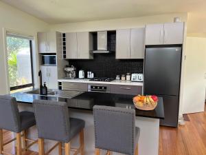 una cucina con un frigorifero nero e un bancone con sedie di Banksia - Great for 2 families, linen included a Venus Bay