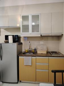 a kitchen with white cabinets and a white refrigerator at Stylish New Studio at McKinley Hill BGC Free Netflix in Manila