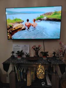 a flat screen tv on a wall with two people in the water at Stylish New Studio at McKinley Hill BGC Free Netflix in Manila +9 photos