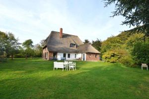 ein Haus mit einem Tisch und Stühlen im Hof in der Unterkunft Reet-Cottage Nahe der Ostsee in Süsel