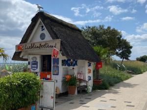 ein kleines Gebäude mit einem Dach an einer Straße in der Unterkunft Reet-Cottage Nahe der Ostsee in Süsel + 10 Fotos