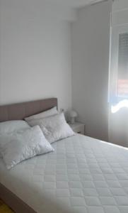 a white bed with two pillows on top of it at For You in Vrnjci