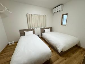 石垣岛I's villa 真栄里石垣島的有两张床和一扇窗户的卧室