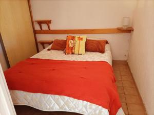 1 dormitorio con 1 cama con manta roja y almohadas en Chez Yamina, en Gruissan