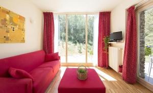 a living room with a red couch and a large window at Ferienwohnung Lampone In San Bernardino Verbano in San Bernardino Verbano