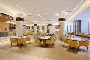 a restaurant with tables and chairs in a room at Howard Johnson Glory Plaza Chenghai in Shantou