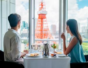 a man and woman sitting at a table in front of a window at The Prince Park Tower Tokyo - Preferred Hotels & Resorts, LVX Collection in Tokyo