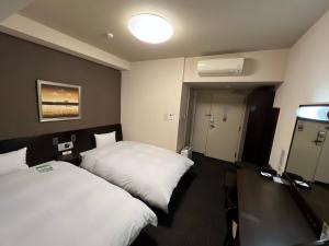 a hotel room with two beds and a light at Hotel Route-Inn Uozu in Uozu